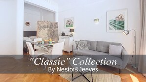 Una sala de estar moderna con comedor, que incluye un sofá gris, sillas blancas, una mesa de comedor con alimentos para el desayuno y obras de arte en las paredes.
