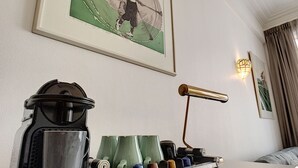 Una estación de café ordenada con una cafetera, tazas y una bandeja de bolsitas de té.
