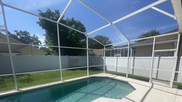 Una piscina con agua cristalina azul, rodeada por una cerca blanca y cubierta por una estructura de techo transparente.