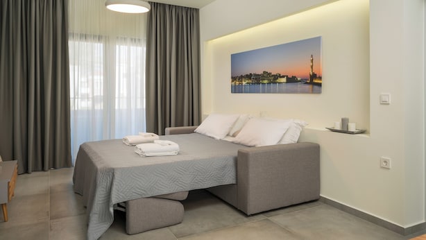 Ein modernes Schlafzimmer mit einem Bett, grauen Vorhängen, einem Stadtbildgemälde und einem Nachttisch mit Lampe.