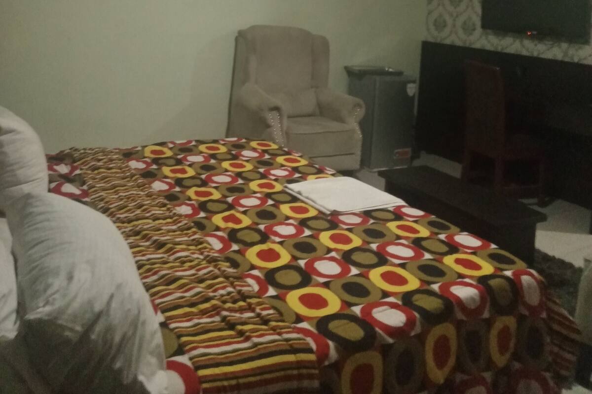 Ein Zimmer mit Bett, Sessel, Fernseher und Klimaanlage.