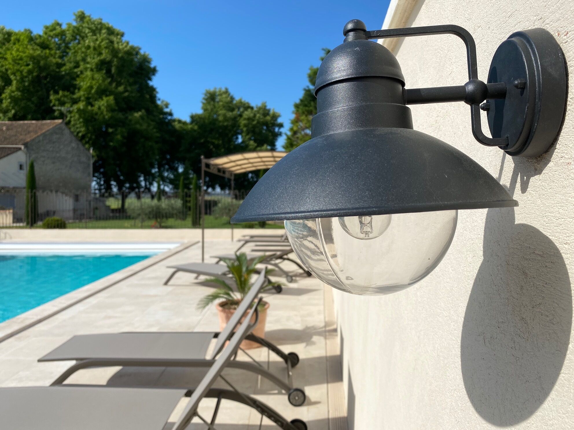 A poolside lamp attached to a wall near a swimming pool.