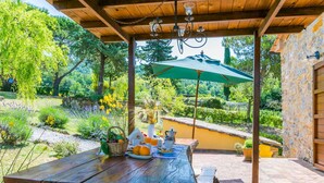 Eine hölzerne Pergola mit gedecktem Tisch, umgeben von einem Garten mit verschiedenen Pflanzen und Blumen.