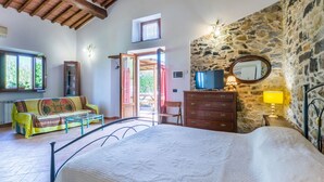 Ein Schlafzimmer mit einem Bett, einer Kommode, einem Fernseher und einer Steinwand.