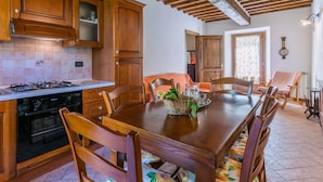 Een traditionele keuken met houten kastjes, een eettafel en stoelen.