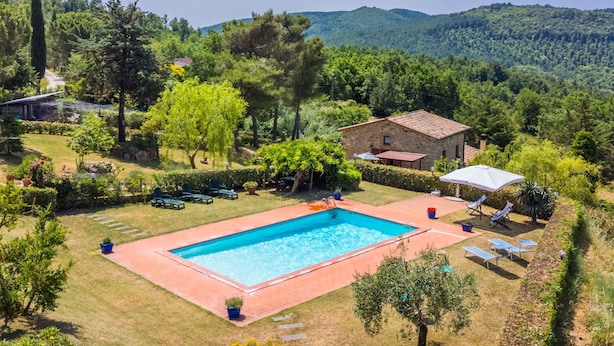A pool area with a stone building, surrounded by lush greenery and hills. - Cosy apartment for 12 people with private pool, A/C, WIFI, TV, patio and pets allowed (Castelnuovo Di Val Di Cecina)