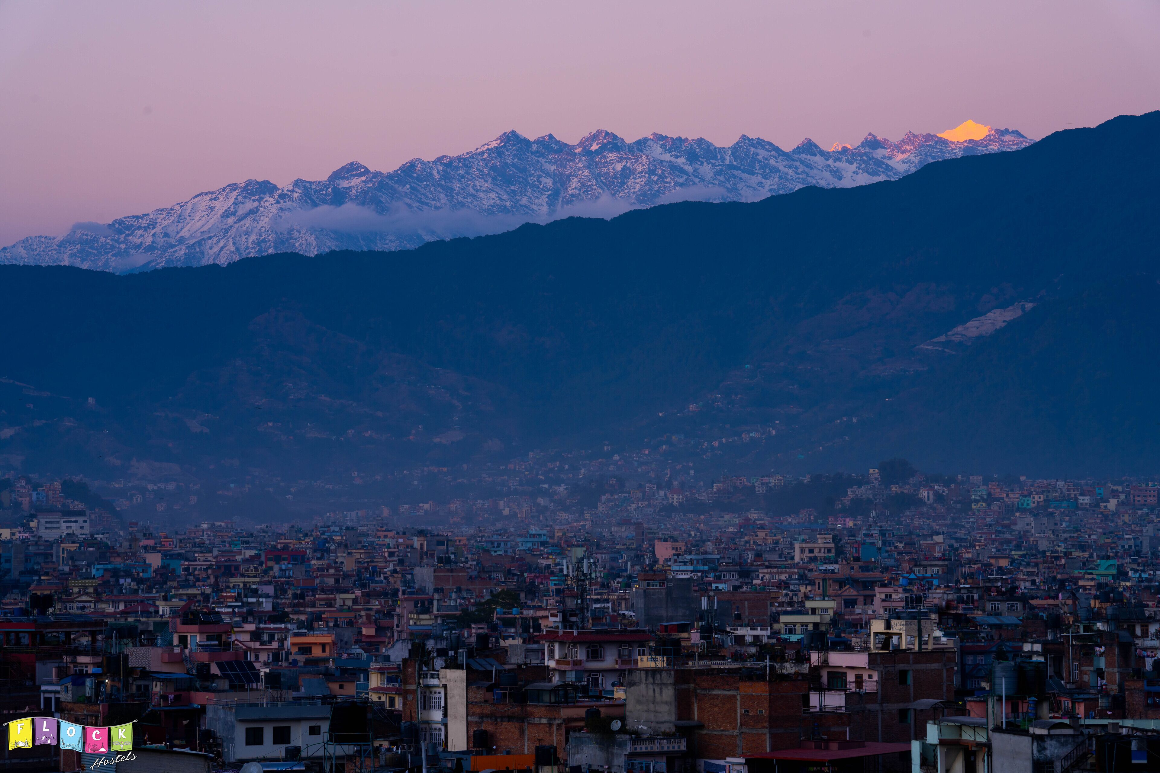 A cityscape with a mountain range in the background.