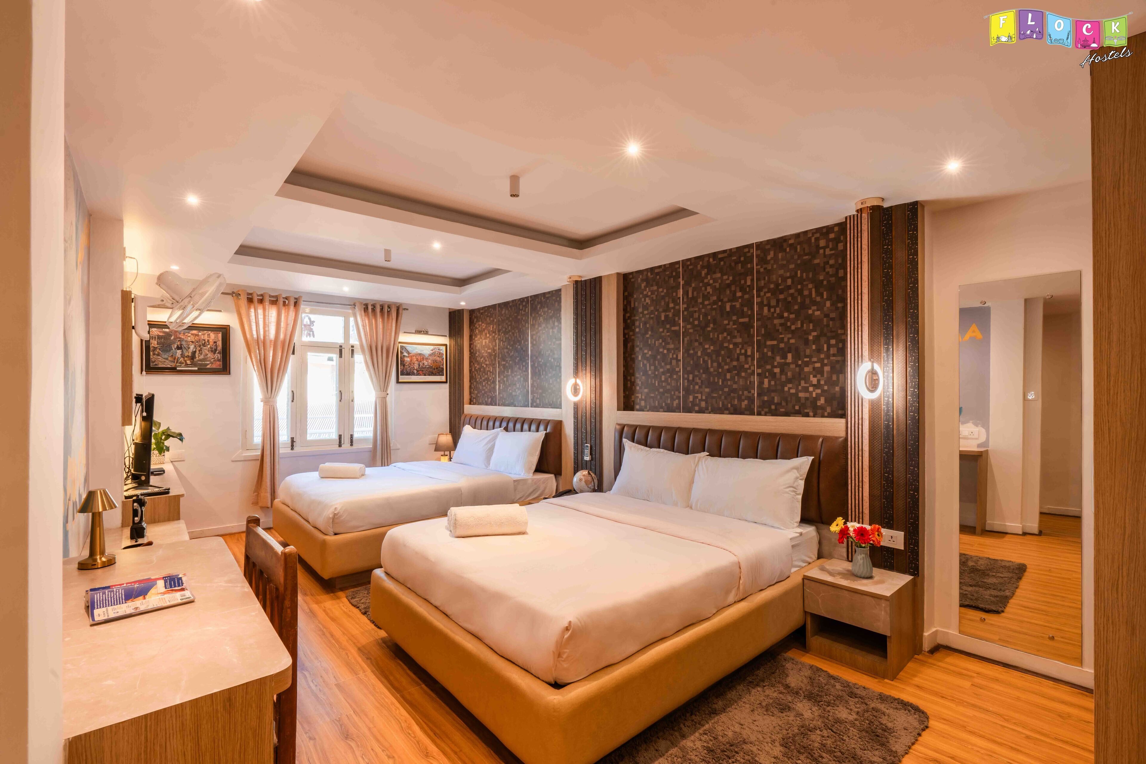 Ein Hotelzimmer mit zwei Betten, einem Schreibtisch und einem Spiegel.