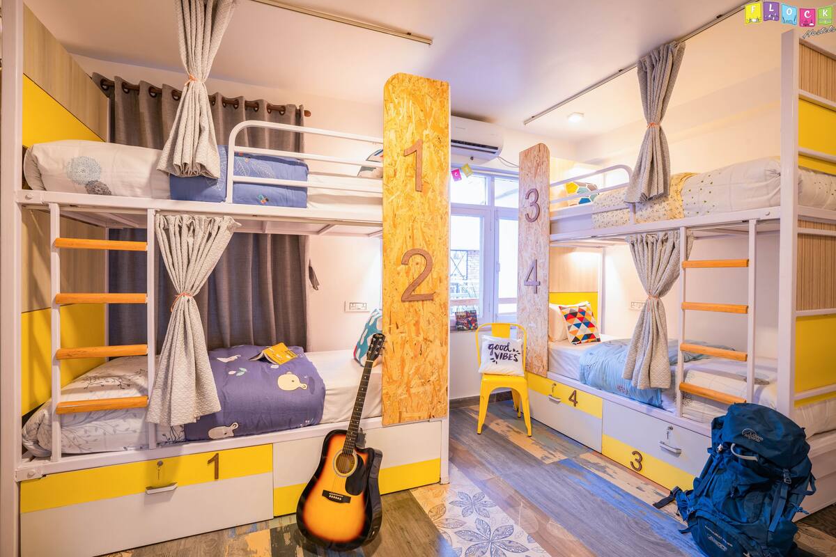 A bunk bed room with numbered beds, a guitar, and a backpack.