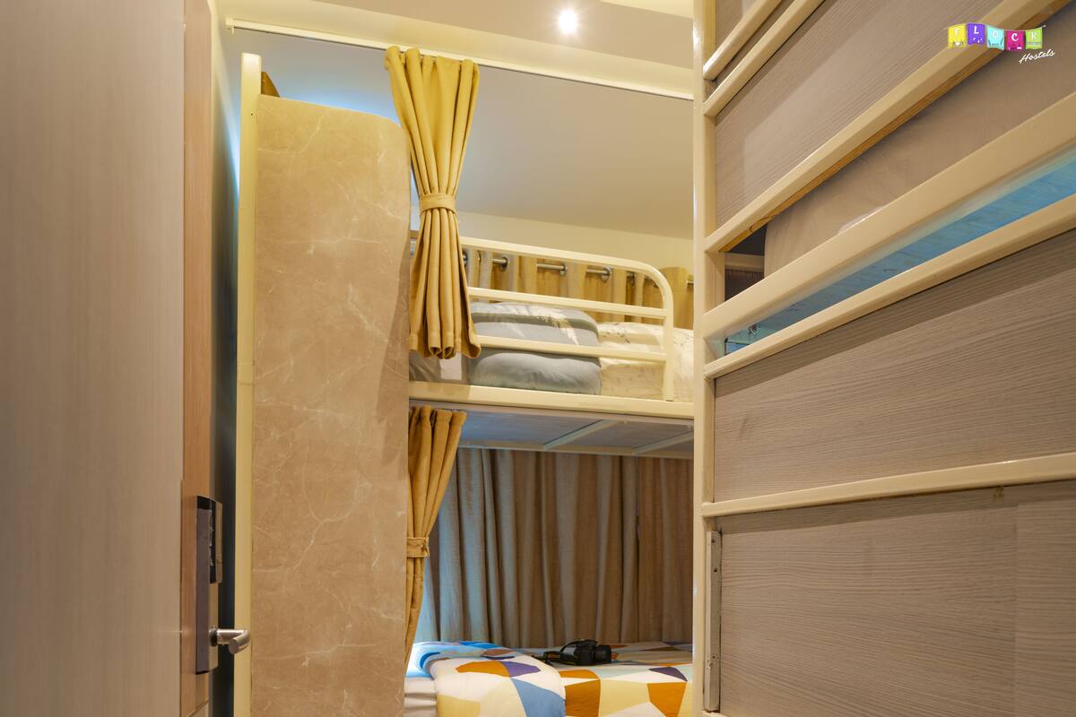 A compact, well-lit room with a bunk bed, a small desk, and a wardrobe.