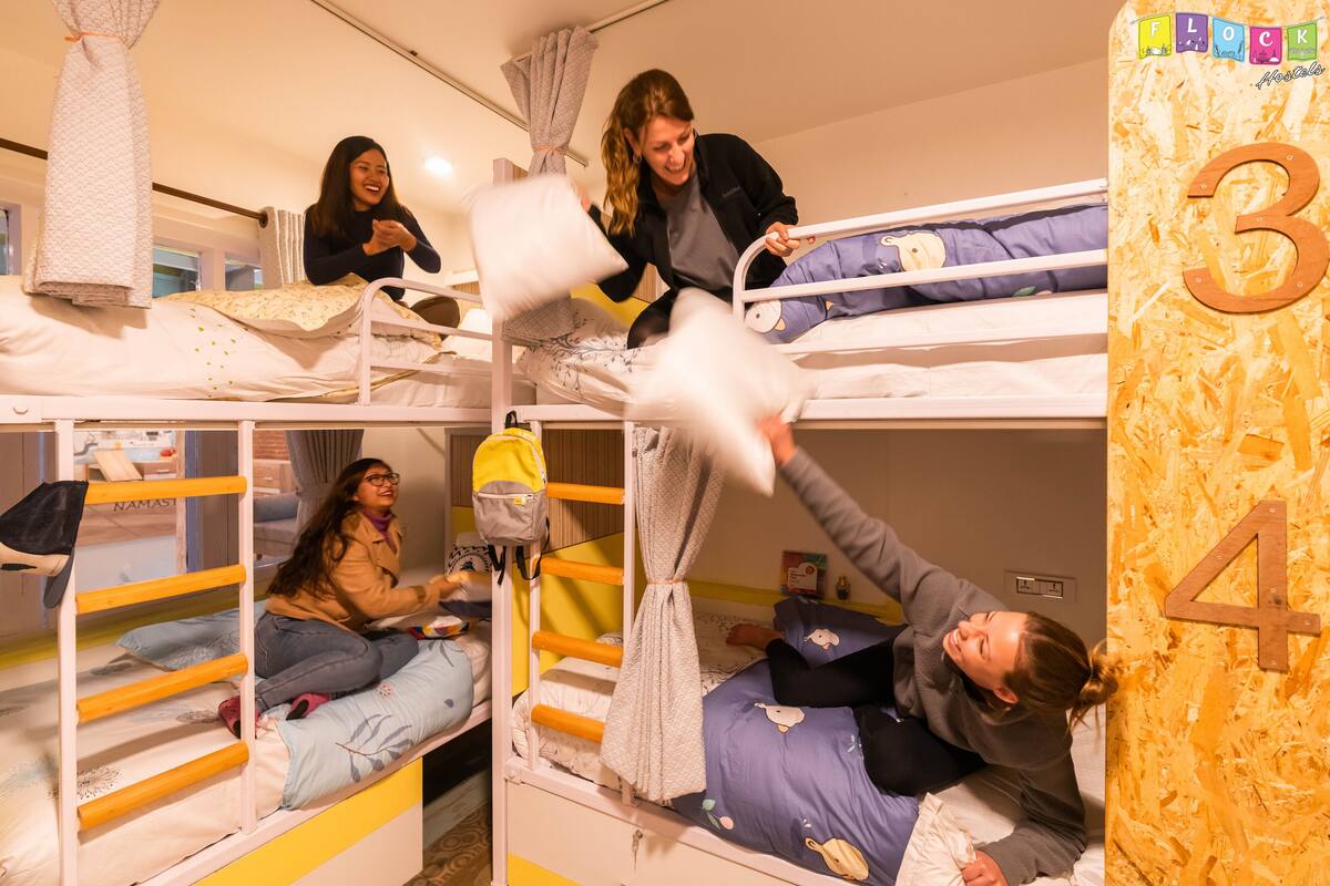 A bunk bed room with multiple beds, a ladder, and a small table.