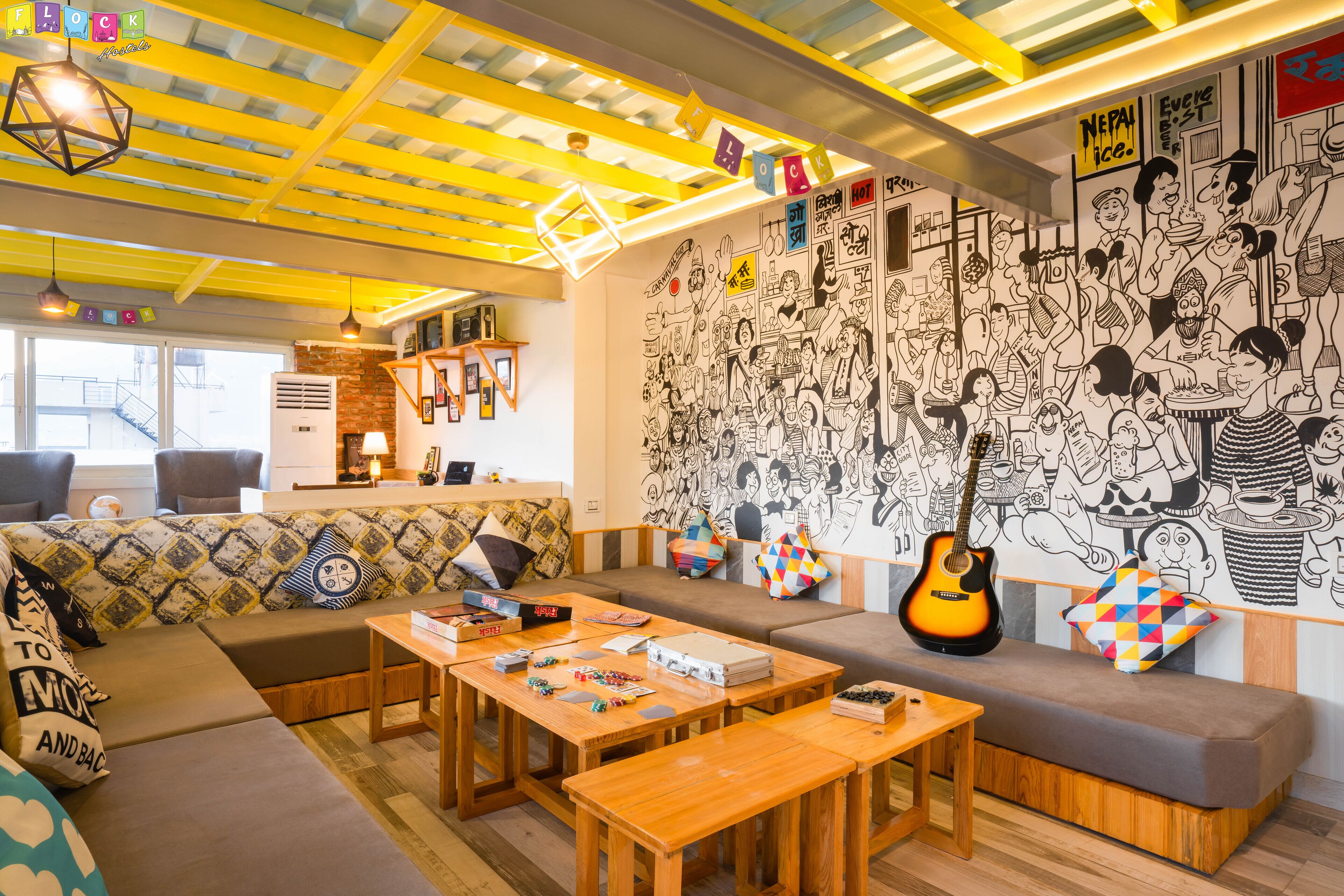 Un espacio de sala acogedor con sofá, mesas de madera y un mural en la pared.