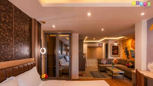 A hotel room with a large bed, a sitting area with a sofa and a coffee table, and a door leading to a hallway. - Flock Kathmandu (Kathmandu)