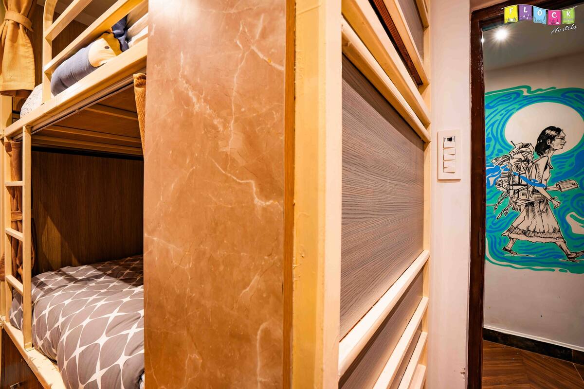 A bunk bed room with a wooden headboard, a patterned bedspread, and a mural on the wall.