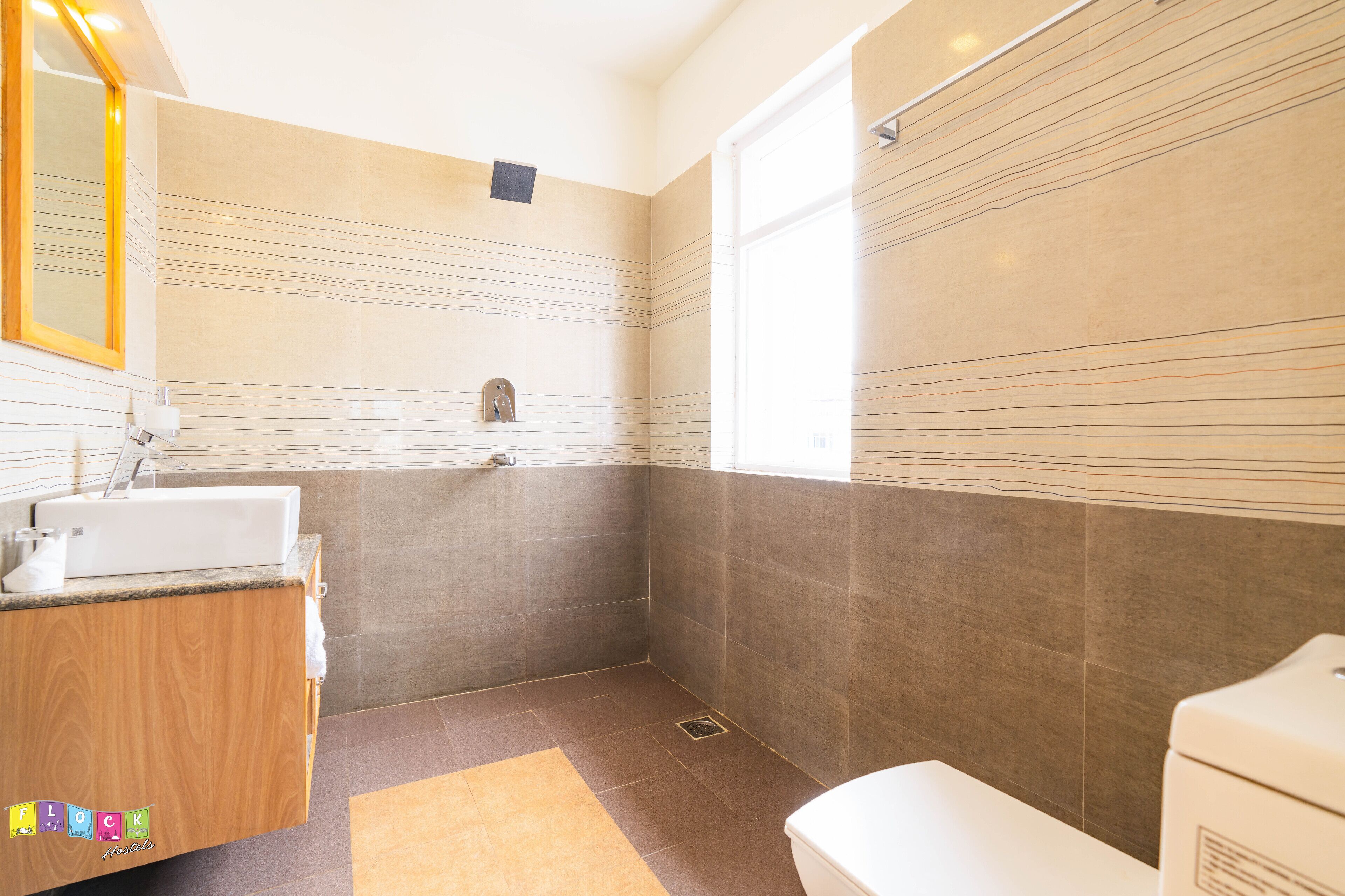 A modern bathroom with a wooden vanity, a toilet, and a shower area.