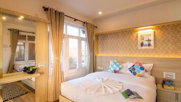 A hotel room with a large bed, a bedside table, a mirror, and a window with curtains.