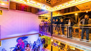 A bar with a stage for live performances, a balcony with people watching, and a variety of bottles on shelves. - Flock Kathmandu (Kathmandu)