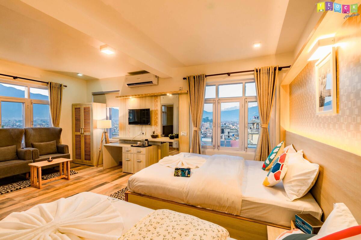 A hotel room with a bed, a sofa, a desk, and a TV.