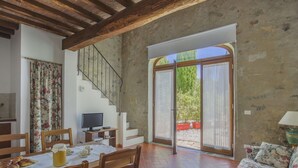 A dining area with a table set for two, a television, and a staircase leading to a balcony. - Cosy apartment in villa for 3 people with pool, WIFI, TV, terrace and pets allowed (Sesto Fiorentino)