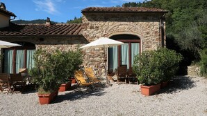 A stone building with a tiled roof, outdoor seating area with chairs and tables, and potted plants. - Cosy apartment in villa for 3 people with pool, WIFI, TV, terrace and pets allowed (Sesto Fiorentino)