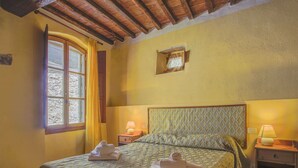 A bedroom with a bed, two bedside tables, a window with curtains, a wooden ceiling, and a small picture frame on the wall. - Cosy apartment in villa for 3 people with pool, WIFI, TV, patio and pets allowed (Sesto Fiorentino)