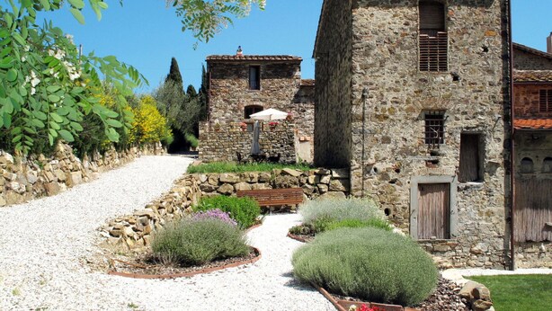 A stone building with a gravel path leading to a bench and a table with an umbrella. - Cosy apartment in villa for 3 people with pool, WIFI, TV, patio and pets allowed (Sesto Fiorentino)