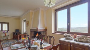 Une salle à manger avec une cheminée, une grande fenêtre offrant une belle vue et une table mise pour le repas.