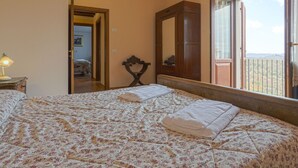 Une chambre à coucher avec un lit, une armoire en bois, un miroir et une fenêtre donnant sur un paysage agréable.