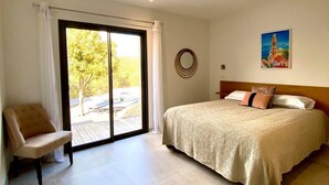 A bedroom with a bed, a chair, a large window, and a painting on the wall. - NEW VILLA **** 145m² - Heated swimming pool - Close to L'Ile-Rousse beaches (MONTICELLO)