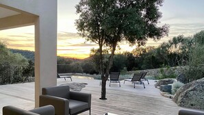 A deck with outdoor seating and a view of the sunset. - NEW VILLA **** 145m² - Heated swimming pool - Close to L'Ile-Rousse beaches (MONTICELLO)