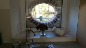 Eine Küche mit Fenster zum Innenhof, einem Spülbecken und einer Blumenvase.