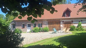 Ein traditionelles Backsteingebäude mit rotem Ziegeldach, einer Holztür und einem Schotterweg.