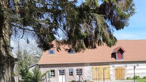 Ein rustikales Steinhaus mit Ziegeldach und einem umzäunten Hof, auf dem Hühner laufen.