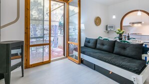 Ein modernes Wohnzimmer mit einer Couch, einem Fernseher und einer Schiebetür zu einem Außenbereich.