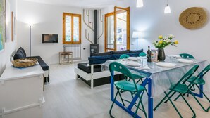 Ein moderner Wohnraum mit Essbereich, einer Couch, einem Fernseher und einem Kamin.