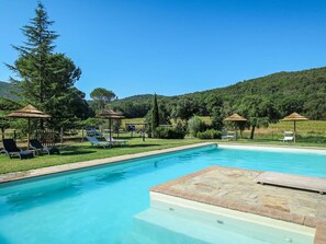 A swimming pool with lounge chairs and umbrellas, surrounded by greenery and hills. - Cosy apartment in villa for 2 people with WIFI, pool, TV, patio, pets allowed and panoramic view (Sticciano)