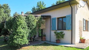 Una casa a un piano con patio, antenna parabolica e piante in vaso.