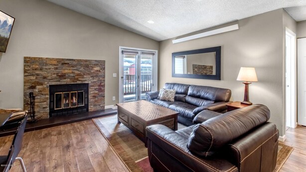 A living room with a stone fireplace, leather sofa, and a dining area with a table and chairs. - Beautiful 2 bd/2 ba condo in the heart of town with all the amenities (Winter Park)