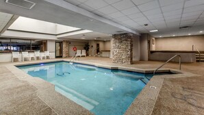 An indoor swimming pool with a stone pillar, a lifebuoy, and a bar area with chairs. - Beautiful 2 bd/2 ba condo in the heart of town with all the amenities (Winter Park)