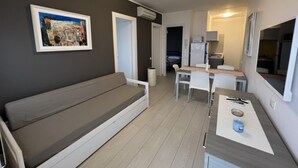 Un espacio habitable compacto con sofá, mesa de comedor y kitchenette.
