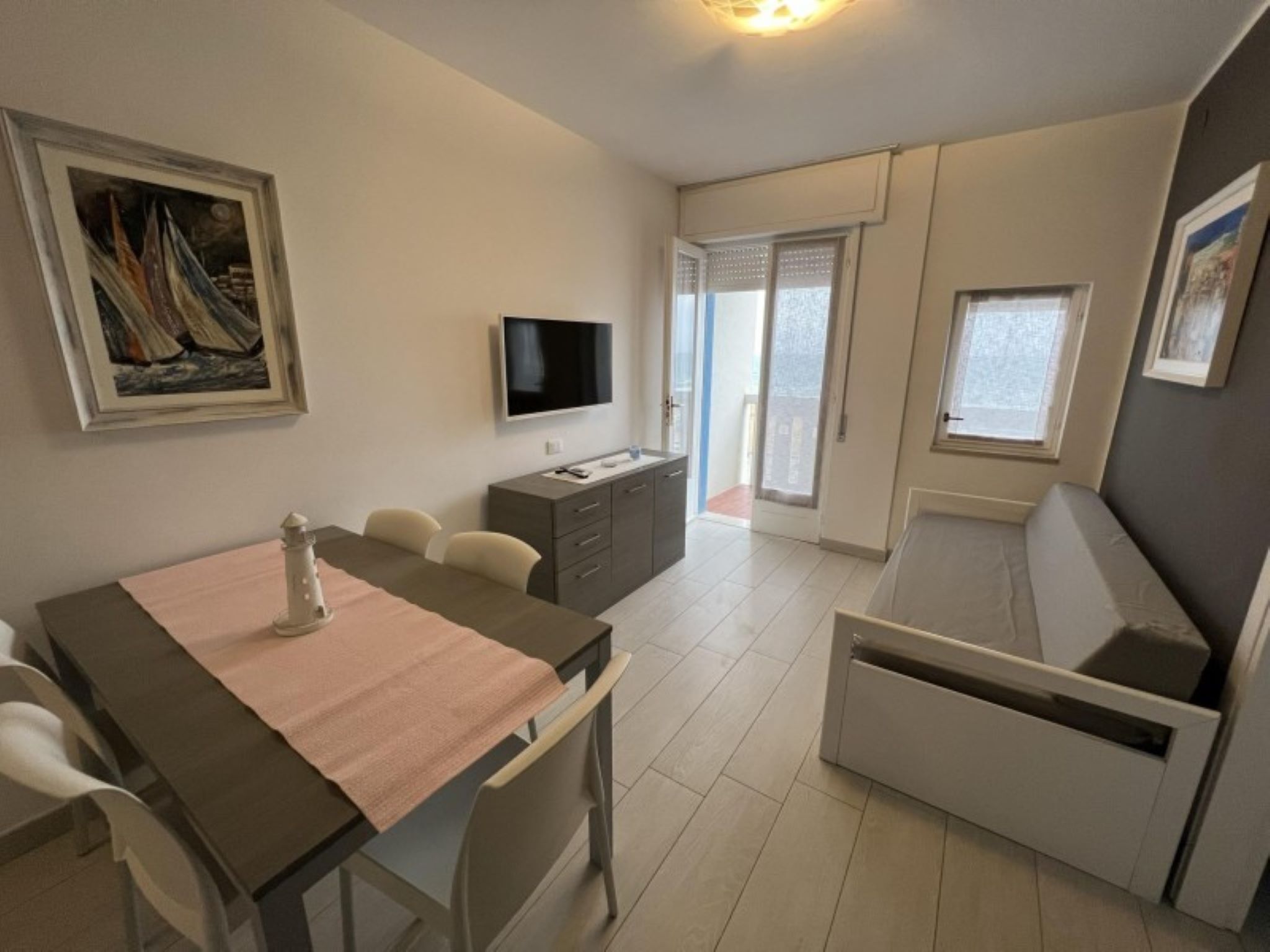 Une pièce de taille modeste comprenant une table à manger, des chaises, un téléviseur, un canapé et un tableau accroché au mur.