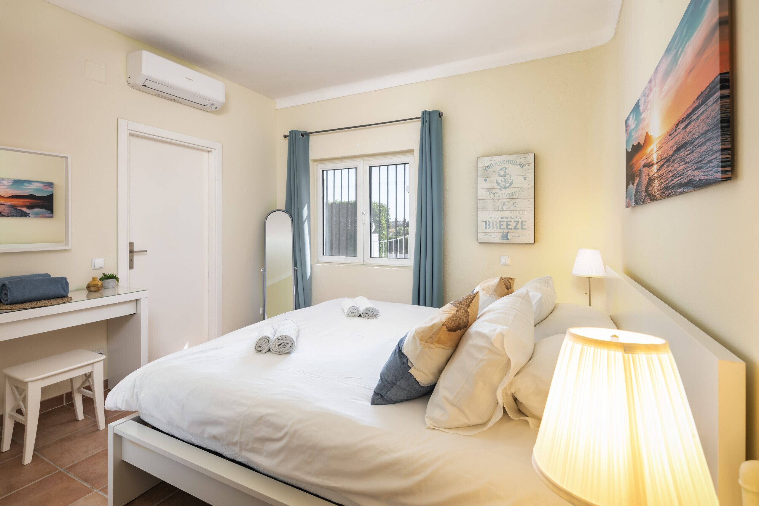 A neatly arranged bedroom with a bed, bedside lamp, and a desk with a chair.