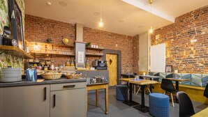A restaurant with brick walls, wooden tables, and blue cushioned seating. - aappartel boardinghouse city center (Bielefeld)