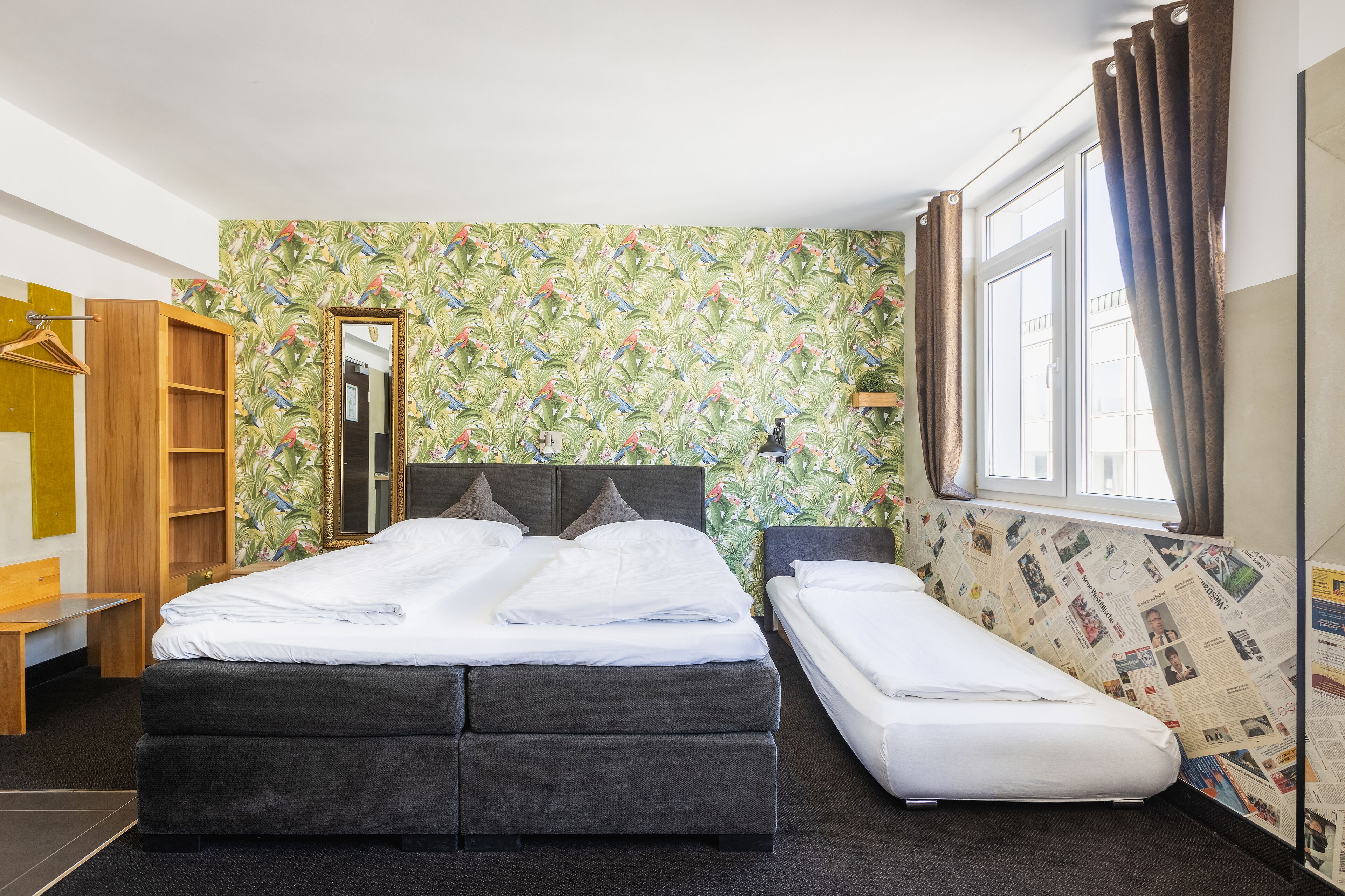 A room with a bed, a bench, a wardrobe, and a window with curtains.
