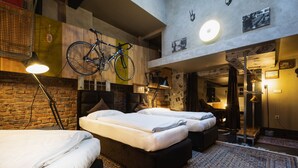 A hotel room with two beds, a bicycle hanging from the ceiling, and a brick wall. - aappartel boardinghouse city center (Bielefeld)