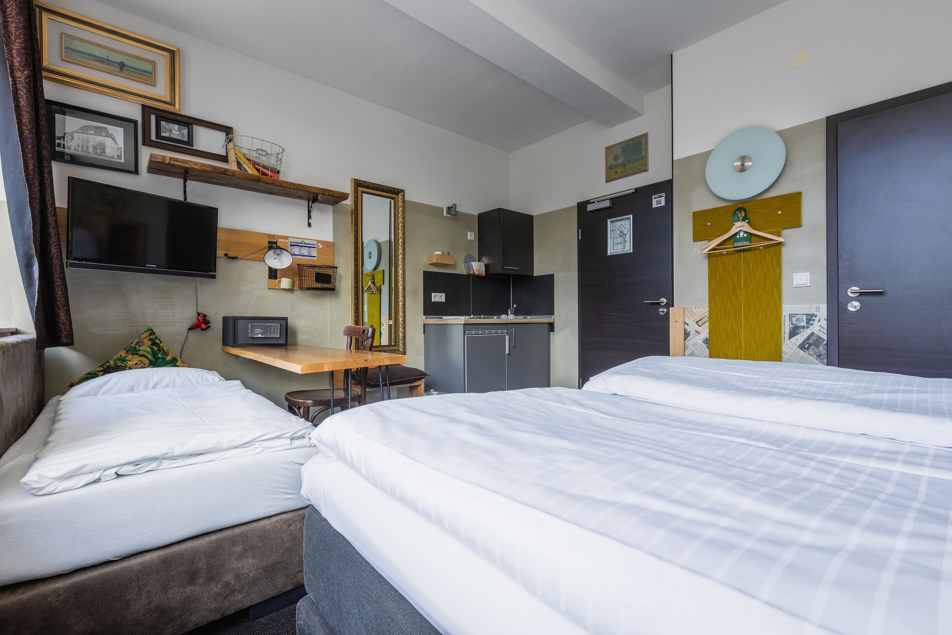 Camera d'albergo con due letti, una TV, una scrivania, uno specchio e un armadio.