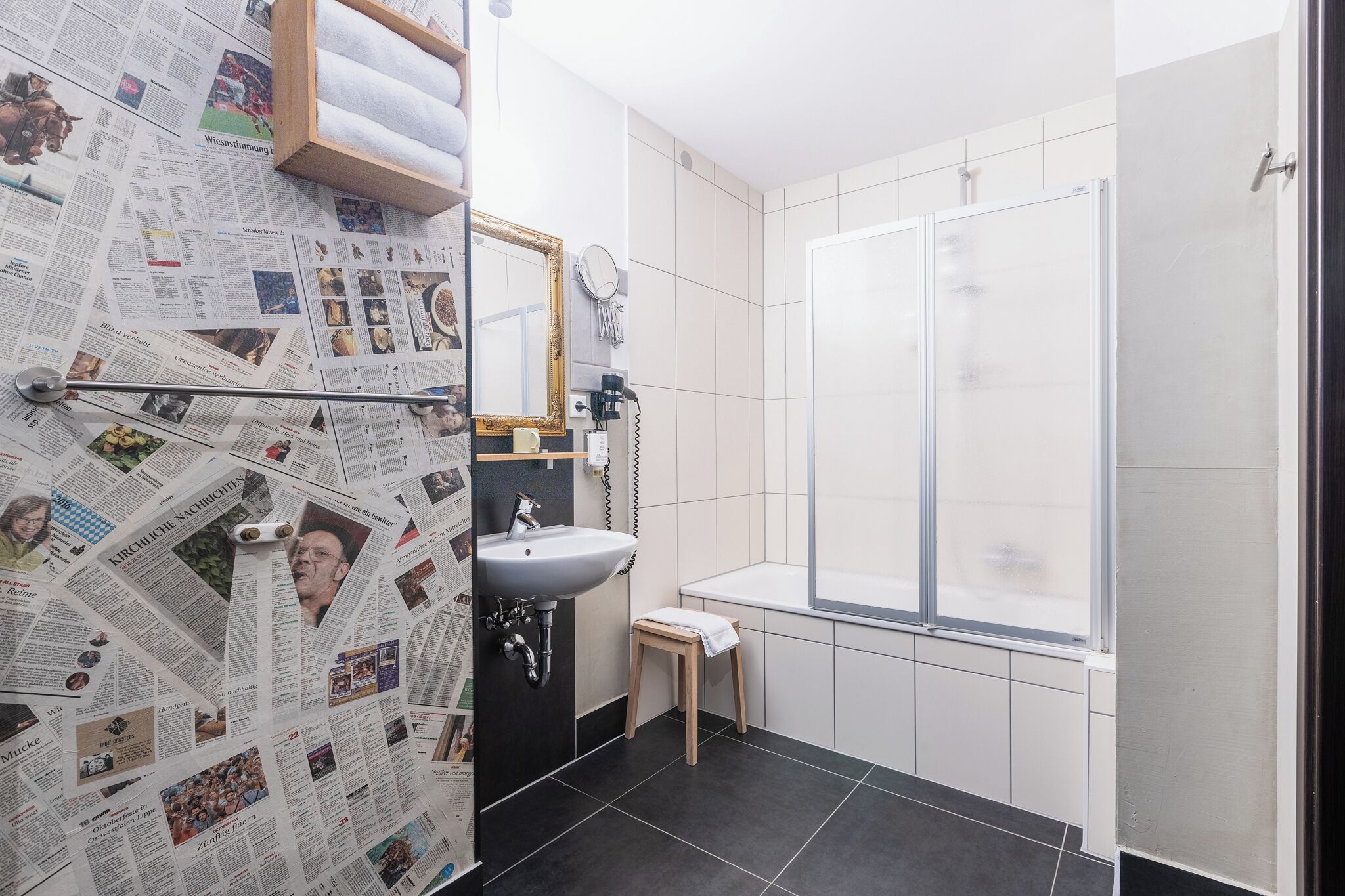 A bathroom with a sink, mirror, and shower.