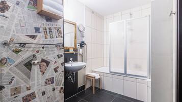 A bathroom with a sink, mirror, and shower.