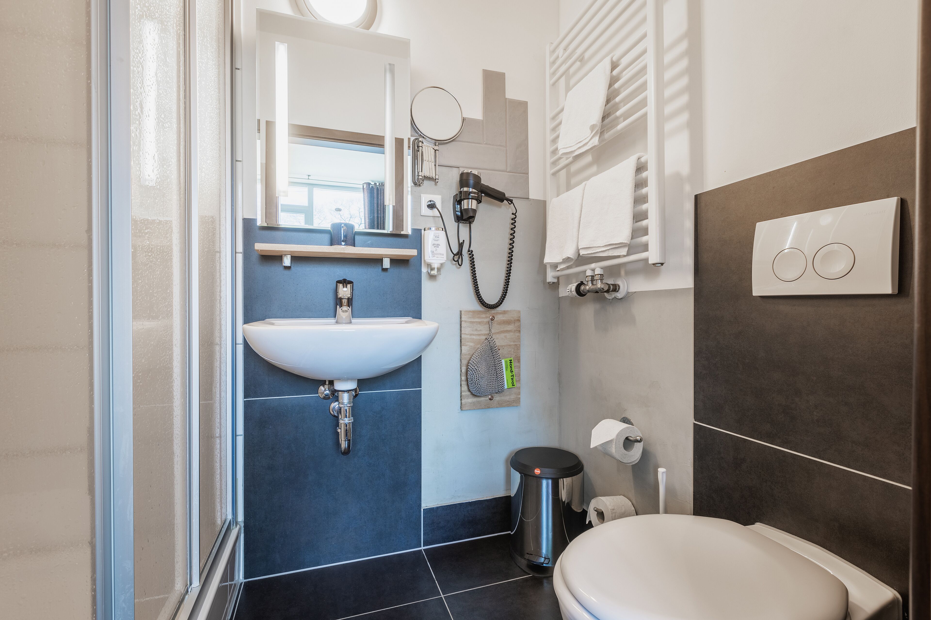 Ein modernes Badezimmer mit Waschbecken, Spiegel, Handtuchhalter und Toilette.