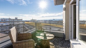 A balcony with wicker chairs and a table, overlooking a cityscape with buildings and a clear sky. - aappartel boardinghouse city center (Bielefeld)